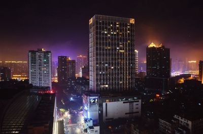 Illuminated buildings in city against sky at night