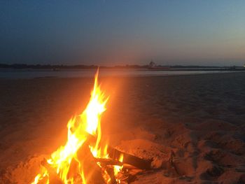 Close-up of bonfire on beach against clear sky