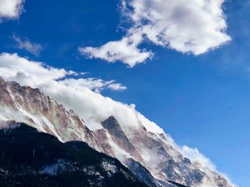 Low angle view of snowcapped mountains against blue sky