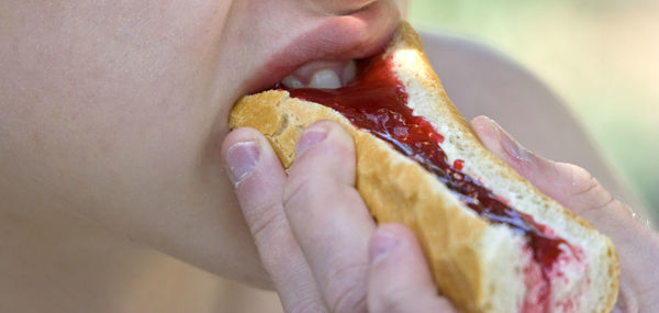 Cropped image of person eating jelly bread