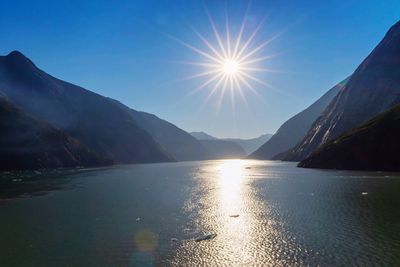 Scenic view of lake and mountains against bright sun