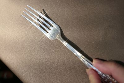 Cropped hand holding fork on textile