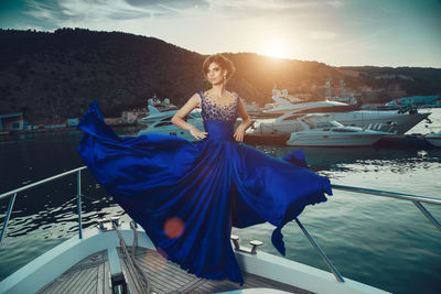 Woman with umbrella on boat against sky during sunset