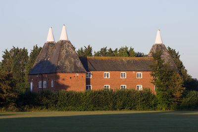 Built structure by trees and building against sky