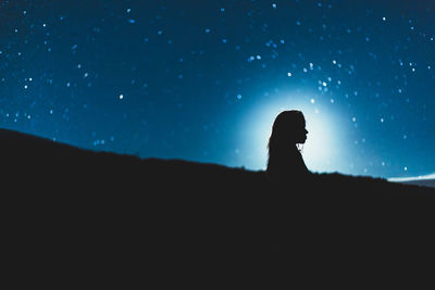Silhouette of man sitting against clear sky at night