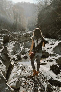 Full length rear view of woman standing on rock