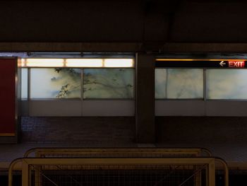 Train at illuminated railroad station platform against sky