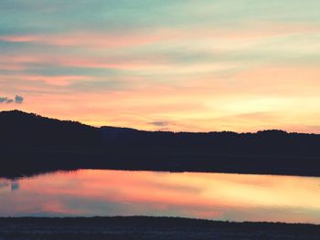 Scenic view of dramatic sky over lake during sunset