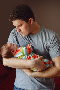 Father carrying son while standing against wall