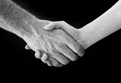 Cropped image of people doing handshake against black background