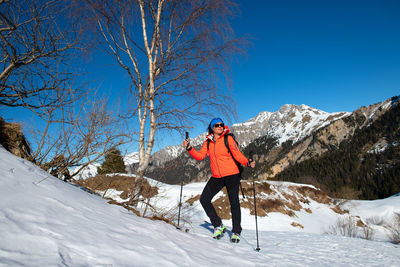 Man standing on snowcapped mountain against blue sky