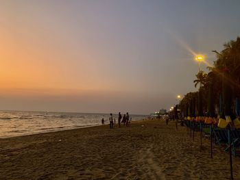 People on beach against sky during sunset