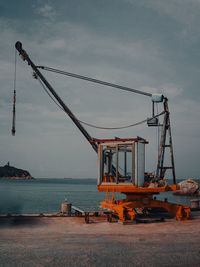 Cranes at commercial dock against sky