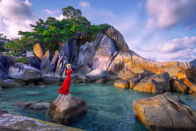 Young woman tourist in red dress standing on hin ta hin yai at koh samui island