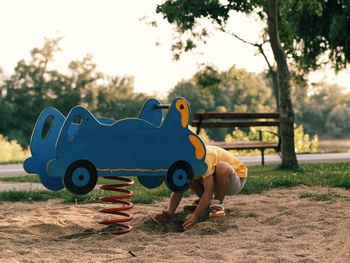 Low section of boy playing with sand at playground in park