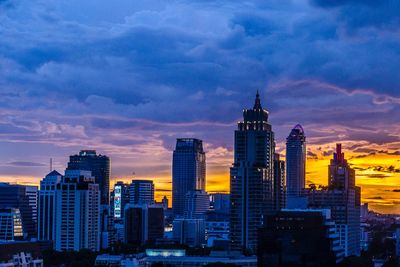 Buildings in city against cloudy sky during sunset