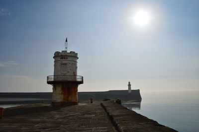 Lighthouse on pier over sea against sky