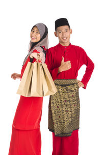 Portrait of smiling couple in traditional clothing with shopping bags against white background