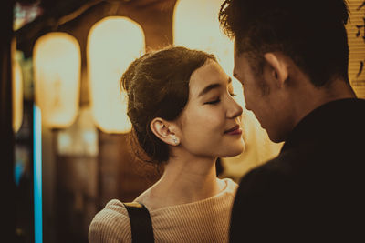 Smiling couple kissing while standing on street in city at night