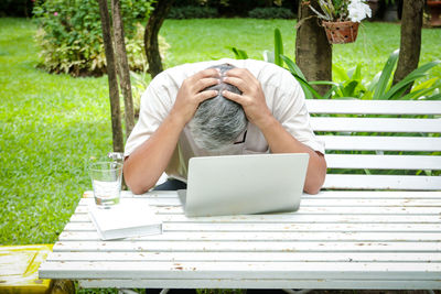 Rear view of man using mobile phone while sitting on table