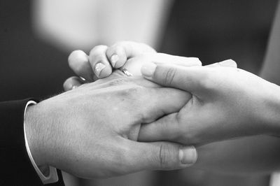 Cropped image of bride exchanging ring with groom during wedding