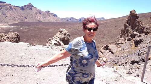 Smiling woman wearing sunglasses while standing on landscape against sky