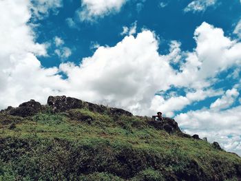 Low angle view of people on rock against sky