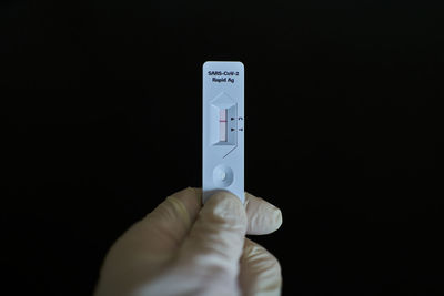 Close-up of hand holding camera over black background