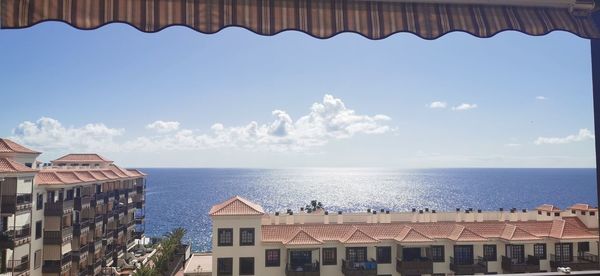 Buildings by sea against sky