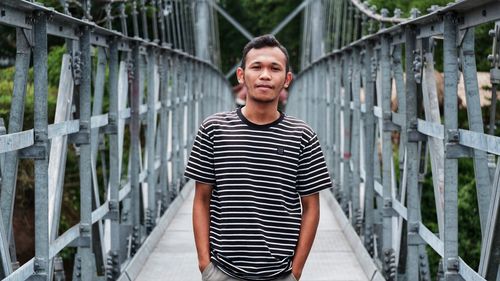 Portrait of smiling man standing on footbridge