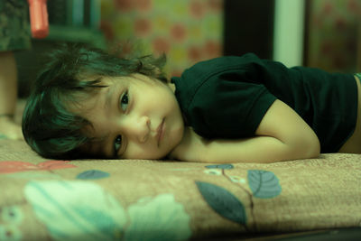 Portrait of cute boy lying on bed at home