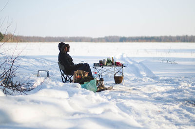 People sitting on snow covered landscape