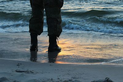 Low section of man standing on beach