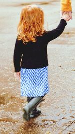 Cropped image of woman with daughter walking on wet road