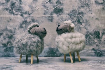 Close-up of sheep figurines on marble by wall