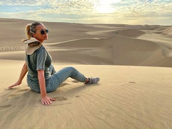 Woman sitting at desert during sunset