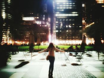 Woman standing on illuminated city street at night