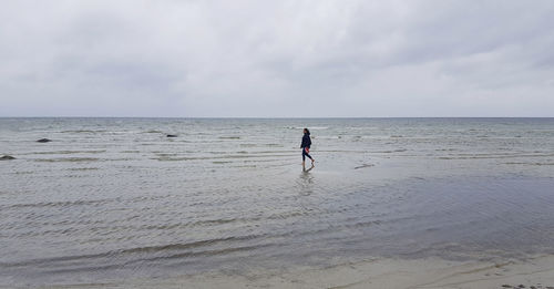 Rear view of man on beach against sky