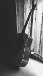 Close-up of guitar against window at home