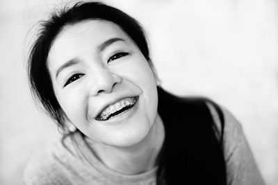 Portrait of cheerful young woman with braces against white background