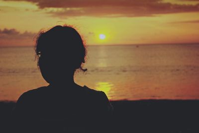 Rear view of silhouette boy on beach against sky during sunset