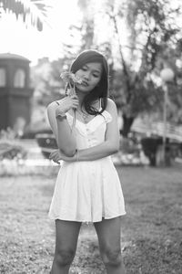 Young woman holding flowers while standing on grass