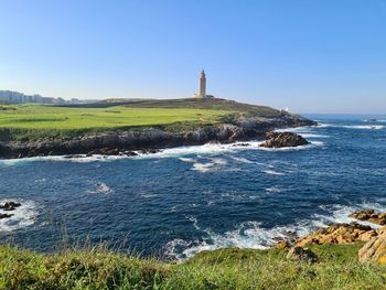 Lighthouse by sea against clear sky