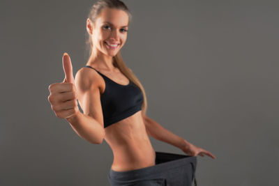 Portrait of mid adult woman in sports clothing standing against gray background