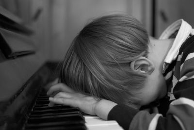 Side view of boy leaning while playing piano