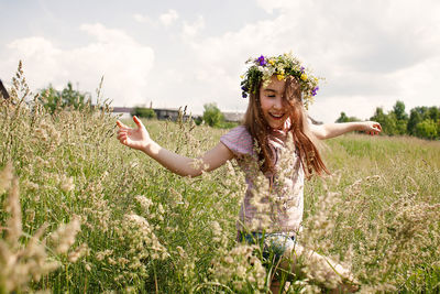 Woman with arms raised on field against sky