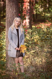 Portrait of woman standing against tree 