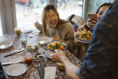 Waiter serving chinese food to customers sitting at restaurant