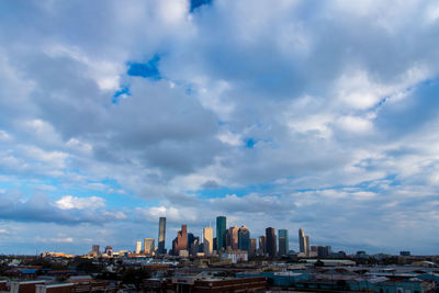 Buildings in city against cloudy sky