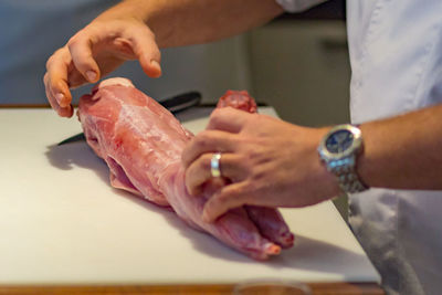 Midsection of man preparing meat on table